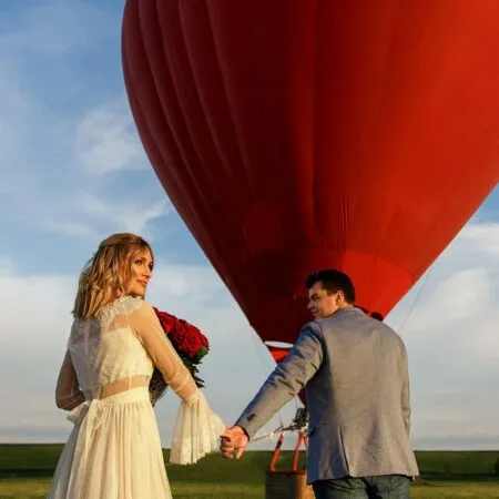honeymoon fund wording - couple bride and groom getting into a red hot air balloon