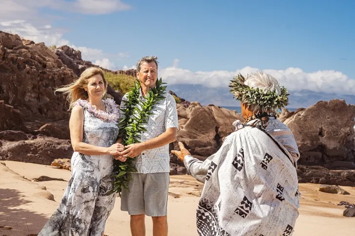 bride and groom holding hands during wedding ceremony on beach