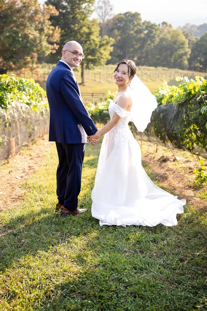 bride and groom smiling and holding hands in winery
