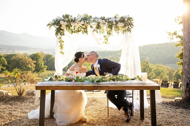 bride and groom kissing at sweetheart table