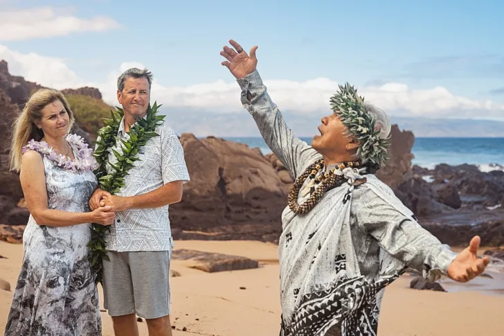 bride and groom watching officiant during wedding ceremony on beach
