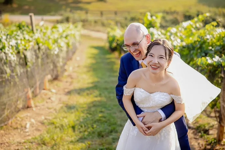 bride and groom embracing and laughing in winery