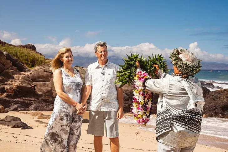 bride and groom holding hands during wedding ceremony on beach