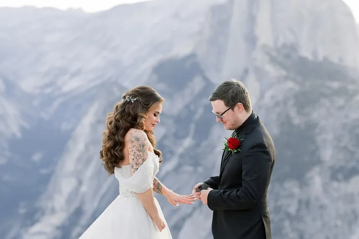 groom putting wedding ring on bride's finger during wedding ceremony