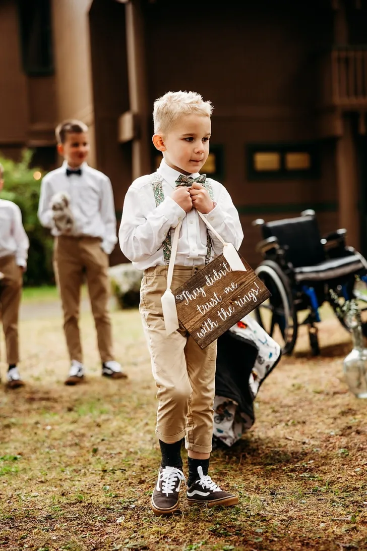 ring bearer walking down the aisle with DIY sign