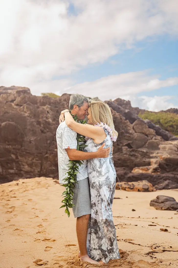 bride and groom embracing and smiling on beach