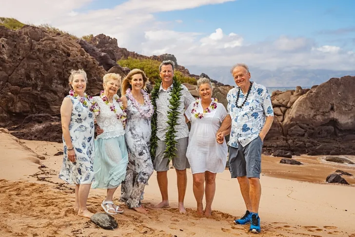 bride and groom posing with wedding guests after wedding ceremony on beach