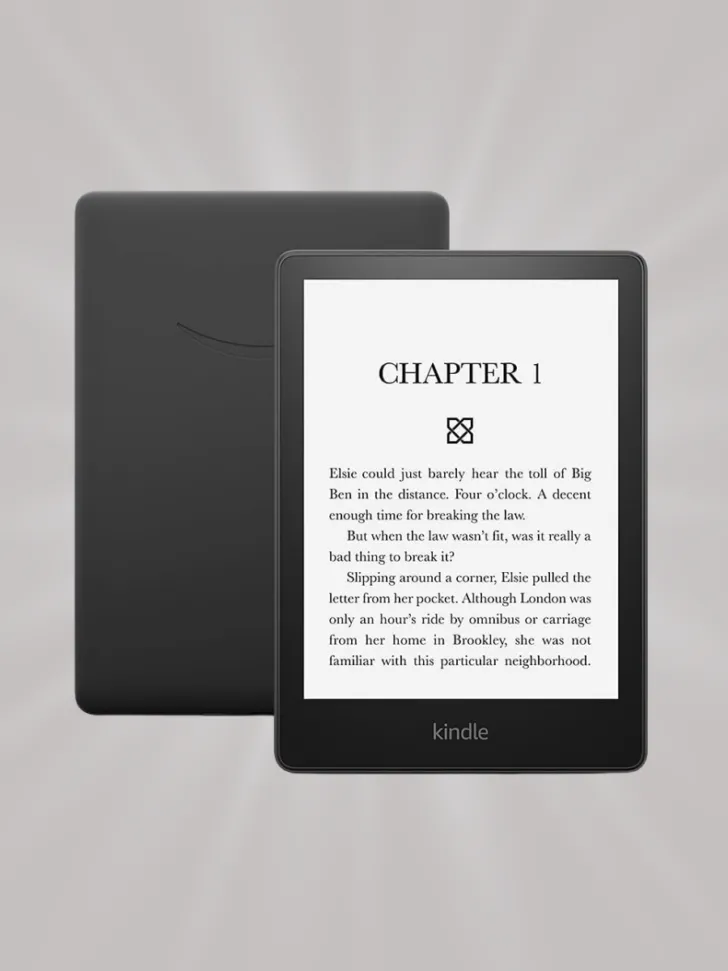 A black Kindle e-reader displaying the beginning of a book on its screen, featuring a minimalist design with a sleek matte finish.