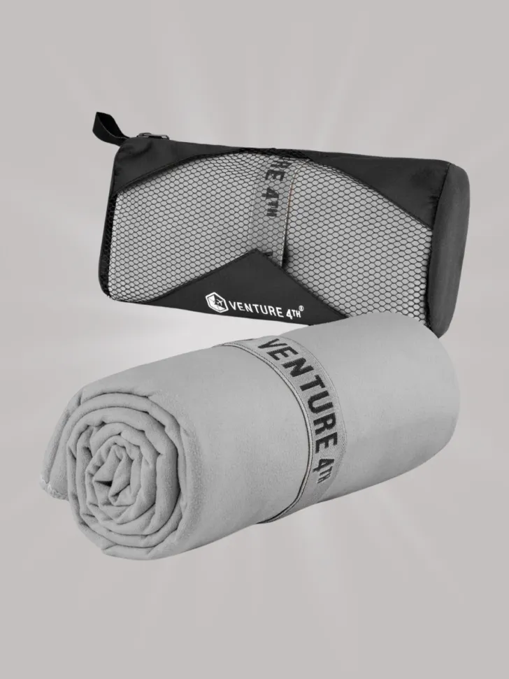 Gray microfiber towel rolled up with "Venture 4th" branding, alongside its black mesh travel pouch.