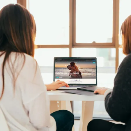 two women looking at a honeymoon registry website on a laptop
